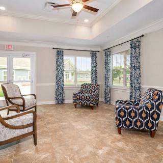 A cozy seating area with patterned armchairs and a ceiling fan in a bright room.