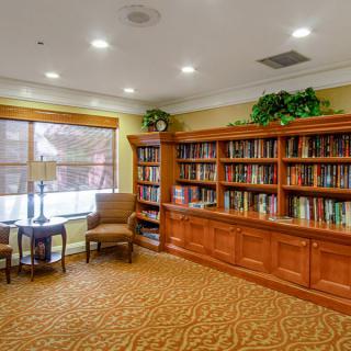 A cozy library room with a large wooden bookshelf and comfortable seating.