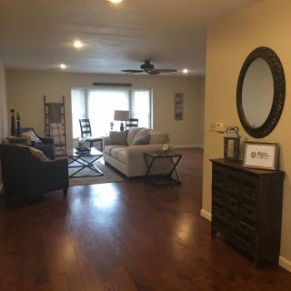 A spacious living room with a sofa set, hardwood floors, and a decorative mirror.