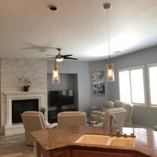 A modern living room with a fireplace, ceiling fan, and stylish seating area.