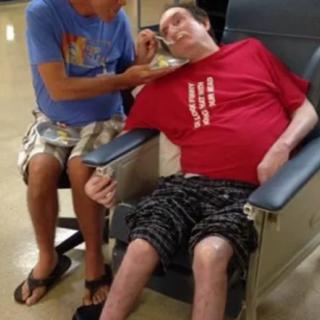 A caregiver assists a patient in a wheelchair at a healthcare facility.