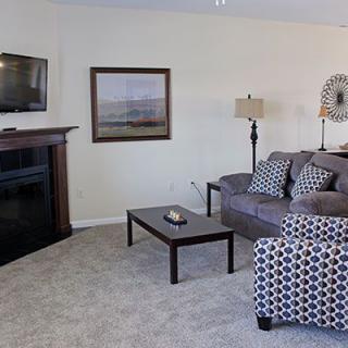A cozy living room with a sofa set, coffee table, fireplace, and television.
