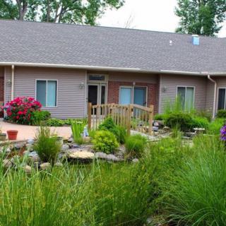 A residential building surrounded by a lush garden with various plants and flowers.