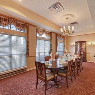 An elegant dining room with a long table set for a meal, surrounded by chairs and illuminated by a chandelier.