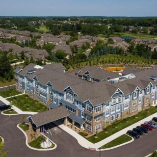 Aerial view of a residential housing complex surrounded by green lawns and neighboring homes.