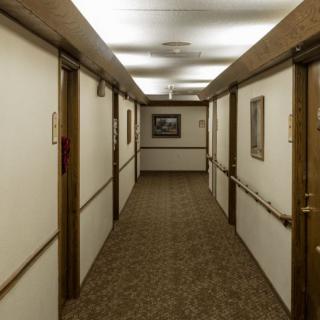 A long hotel hallway with doors on either side and a carpeted floor.