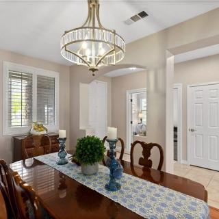 A well-decorated dining room featuring a wooden table, elegant chandelier, and decorative elements such as candles and a plant centerpiece.