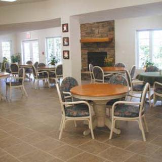 An indoor dining area with tables and chairs arranged around a central fireplace.