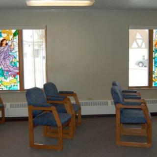 A waiting room with wooden chairs and colorful stained glass windows.