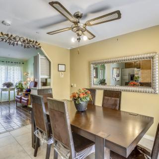 A cozy dining room with a wooden table, cushioned chairs, and a large mirror on the wall.