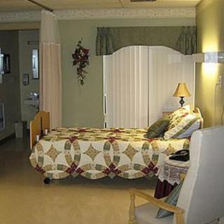 A well-decorated hospital room featuring a bed with a patterned quilt, a small bedside table, and soft lighting.