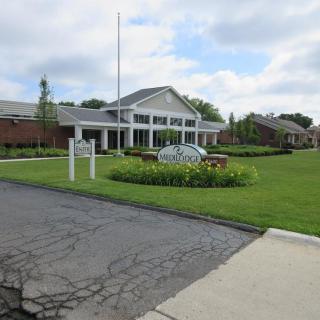 A large building with a well-maintained lawn and driveway under a cloudy sky.