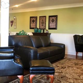 A cozy living room with a black leather sofa and decorative wall art.