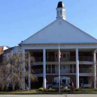 A large building with columns and a cupola, featuring an American flag in front.