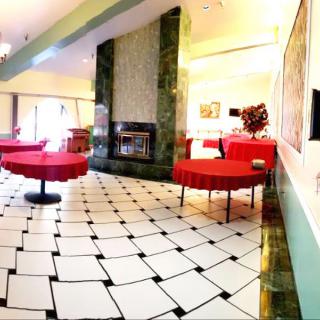 A spacious restaurant interior featuring red tablecloths and a checkered floor.