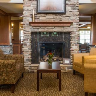 A cozy lounge area featuring a stone fireplace, comfortable seating, and a small table.