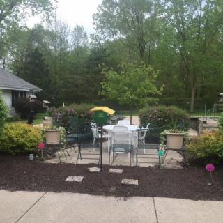 A well-maintained patio area with outdoor furniture surrounded by lush greenery.