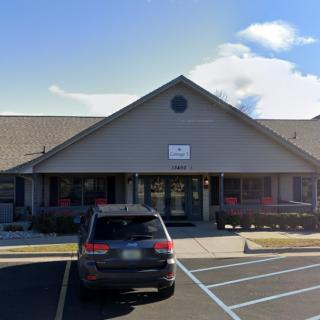 A small commercial building with a car parked in the parking lot on a cloudy day.