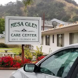 Exterior view of the Mesa Glen Care Center with a focus on its signage and surrounding landscape.