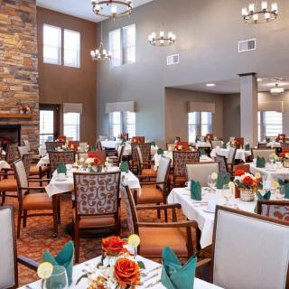 An elegantly set dining room with neatly arranged tables and chairs, featuring decorative elements such as flowers and folded napkins.