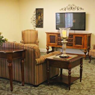 A cozy living room with a television, patterned sofa, and wooden furniture.