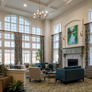 A spacious and elegantly designed living room featuring high ceilings, large windows, and sophisticated furniture arrangements.