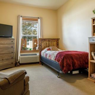 Cozy bedroom with a single bed, dresser, and television.