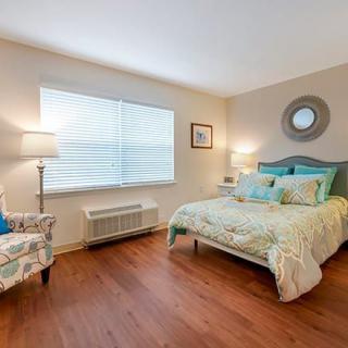 A cozy bedroom with a bed, armchair, and warm lighting.