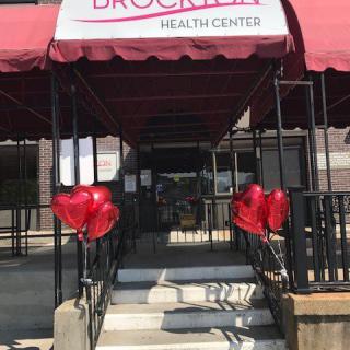 Entrance of a health center with a red awning and heart-shaped balloons.