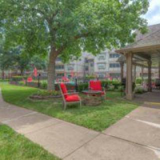 A peaceful garden setting with red chairs, a gazebo, and lush greenery.