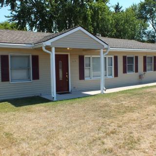 A ranch-style house with a front yard in a suburban area.