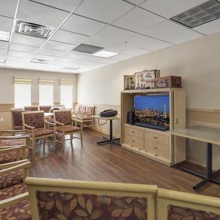 An empty waiting room with multiple chairs and a television.