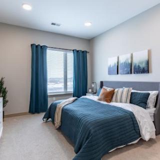 A serene and modern bedroom featuring a calming blue color palette and cozy bedding.