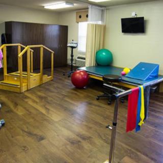 A physical therapy room equipped with various rehabilitation tools such as therapy balls, parallel bars, and resistance bands.
