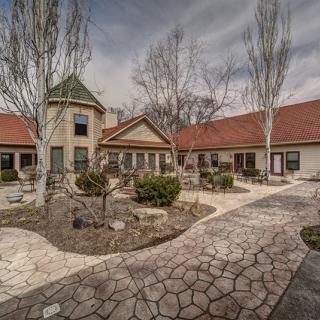 A serene courtyard with a stone pathway and red-roofed buildings under a cloudy sky.