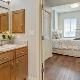 A cozy bedroom and adjoining bathroom with wooden cabinetry and a clean, bright aesthetic.