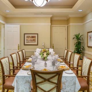A well-decorated dining room with an elegantly set table and chairs, featuring a floral centerpiece and sophisticated lighting.