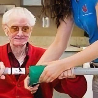 An elderly person receiving physical therapy assistance from a caregiver.