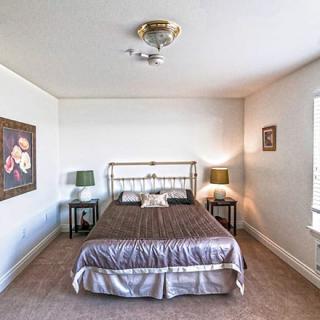 A cozy bedroom with a metal-framed bed, two side tables with lamps, and artwork on the walls.