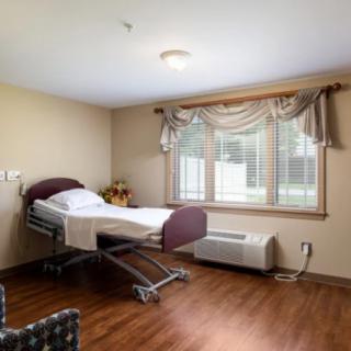 An empty hospital room with a single patient bed and a window with curtains.