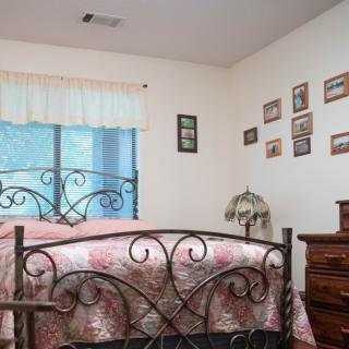A cozy bedroom with a decorative metal bedframe, floral bedding, and walls adorned with framed photos.