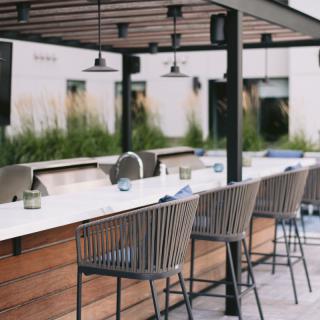 A stylish outdoor bar and dining area with modern furniture.