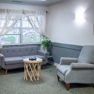 A cozy living room setup featuring a gray sofa, an armchair, and a stylish coffee table with a plant by the window.