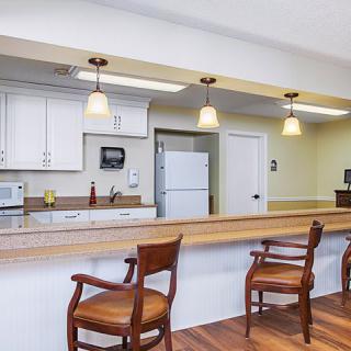 A well-lit kitchen with a wooden counter and chairs, featuring pendant lighting and modern appliances.