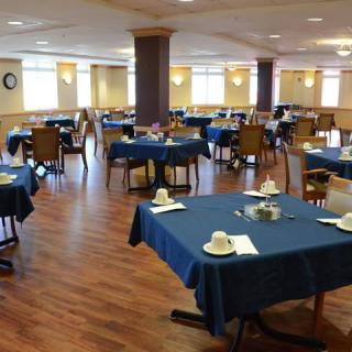 An empty dining room with blue tablecloths and neatly arranged table settings.