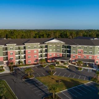 Aerial view of a modern apartment complex with colorful facades and a large parking area.