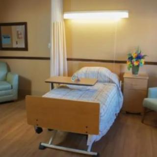 A clean and tidy hospital room with a single bed and seating area.