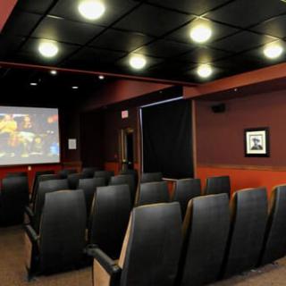 A cozy home theater with rows of comfortable seating facing a large projector screen.