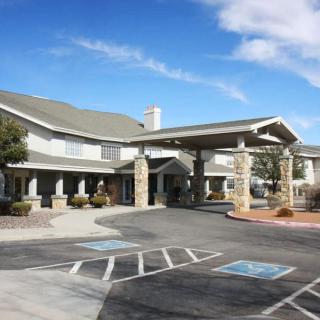 A building with a covered entrance and adjacent parking lot under a partly cloudy sky.