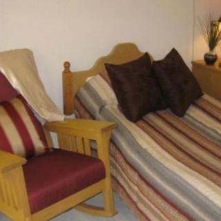 A cozy bedroom featuring a bed with striped bedding and a wooden chair with matching cushions.